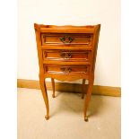 A French chestnut finished three drawer bow front bedside cabinet with tray top