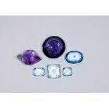 A collection of six unmounted gemstones - blue topaz and amethysts.