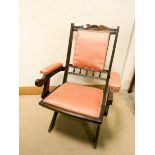 An Edwardian walnut folding campaign chair upholstered in pink material