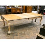 A large late Victorian light oak extending dining table standing on carved legs with leaves and