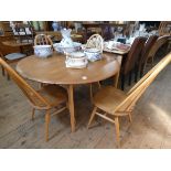 An Ercol light elm drop leaf dining table together with four stick back Windsor style chairs