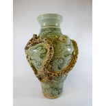 A Chinese pottery vase decorated in relief with a coiled dragon on a celadon green figured ground,