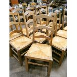 A set of thirteen French light oak ladder back dining room chairs with rush seats