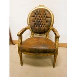 A French gilt framed elbow chair with brown leather upholstered seat and buttoned leather back