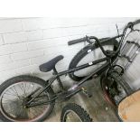 A young person's black BMX style push bike with a set of front forks and a new bicycle tyre