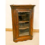 A late Victorian oak corner cupboard with glass door