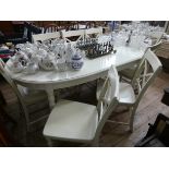An oval cream painted extending dining table with centre leaf and six matching chairs with wood