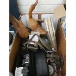 A box containing cameras, two old phones, books, wooden ornaments,