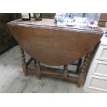 An oval oak gate legged table on barley twist legs,