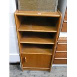 A teak shelf unit with cupboard in base,