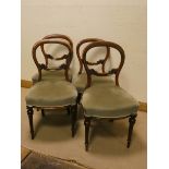 A set of four Victorian walnut balloon backed dining room chairs standing on reeded legs with green