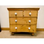 A Victorian stripped pine chest of two long and two short drawers with porcelain bun handles,