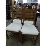A set of four heavy oak ladder back dining room chairs with cream upholstered seats