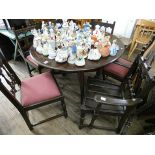 An Ercol oak drop leaf dining table and a set of six spindle back chairs with pink upholstered