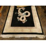 A large black and cream bordered Chinese rug with dragon centre - approximate size 100 inches x 60
