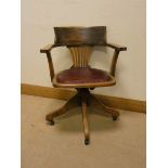 An oak revolving tub shaped office elbow chair with leather seat