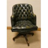 An antique style buttoned green leather revolving office elbow chair with brass studs
