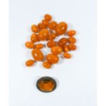 A collection of loose amber beads and an oval citrine brooch