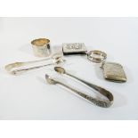A collection of small silverware to include match case, sugar nips, napkin ring,