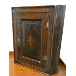 A small antique oak wall hanging corner cupboard with star shape inlay to the door