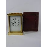 A brass carriage clock in its original red maroon leather carrying case,