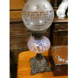 A Victorian iron based oil lamp with decorative pink glass bowl and a shade Fount