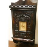 A Victorian carved oak small wall hanging corner cupboard with picture panel centre