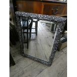 A bevelled wall mirror in decorative silver frame