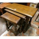 A nest of three heavy reproduction oak coffee tables on turned legs and a small nest of two coffee