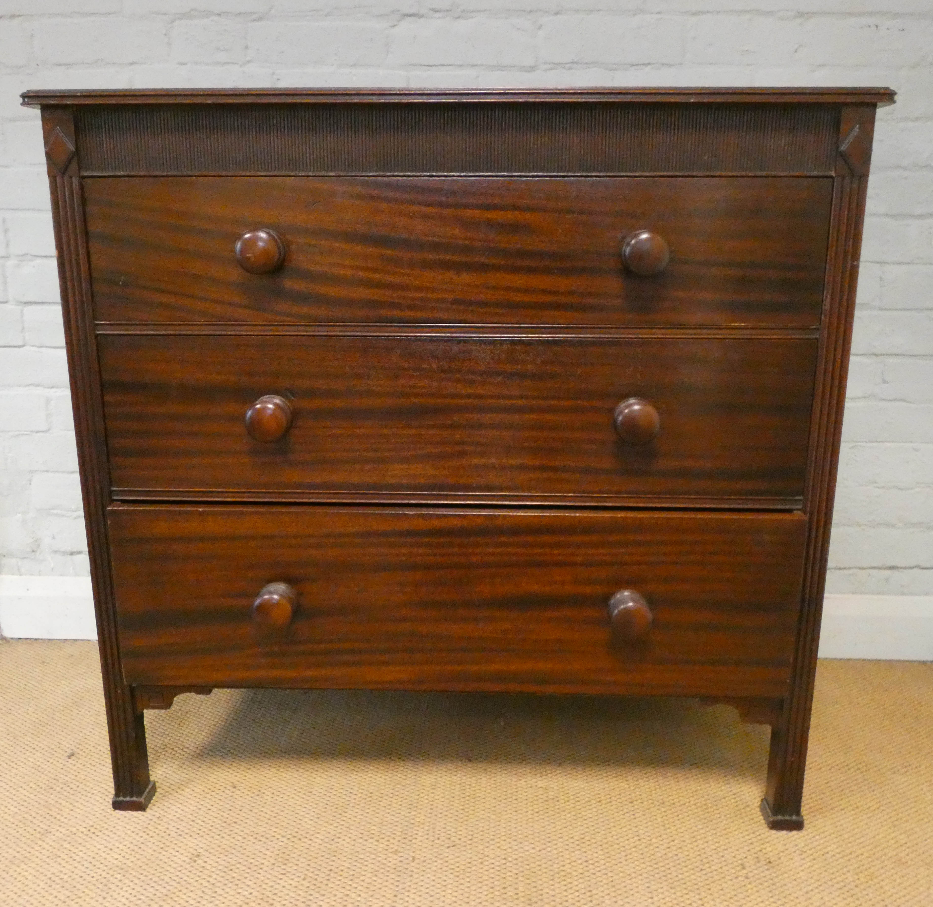Victorian mahogany chest of three long drawers with bun handles standing on reeded style legs