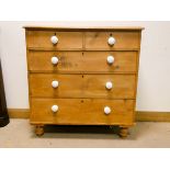 A Victorian stripped pine chest of three long and two short drawers with white porcelain bun