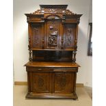 A large French carved oak buffet cabinet with a three door cupboard top,