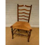 An antique oak ladder back dining chair with rush seat
