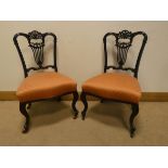 A pair of Edwardian ebonised occasional chairs standing on cabriole legs with striped upholstered