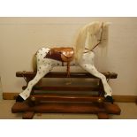 A large dapple grey wooden rocking horse with leather saddle etc on wooden base