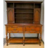 An antique style oak dresser with shelf and cupboard back standing on a base fitted two deep