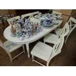 An oval cream painted extending dining table with centre leaf and six matching chairs with wood