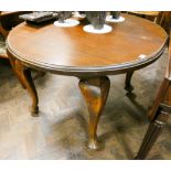 An Edwardian circular mahogany dining table standing on cabriole style legs,