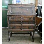 A Jacobean style oak bureau with three long drawers under, standing on barley twist legs,