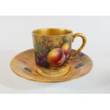 A Royal Worcester cabinet cup and saucer painted with still life fruit panels in a gilded boarder,