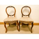 A pair of Victorian walnut balloon back chairs on cabriole legs with upholstered seats