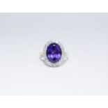 An 18ct oval amethyst and diamond cluster ring, ring size Q, approximate weight 7.