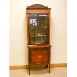 An Edwardian inlaid mahogany china display cabinet standing on a bow front cupboard base decorated