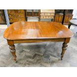 A late Victorian mahogany extending dining table with two leaves standing on turned legs,