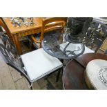 Circular grey metal patio table with glass top and a pair of matching chairs with cushions