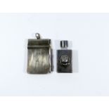 A miniature silver scent bottle decorated with a rose accompanied by a small silver notebook and