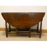 An antique style circular oak gate legged table on turned legs,