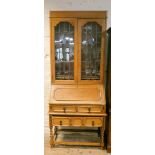 A 1930's light oak leaded glazed bureau bookcase, standing on barley twist legs,