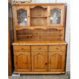 A modern light pine kitchen dresser with glazed back, three drawers and doors under,
