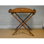 A Victorian oak butlers tray with fold down sides on a folding stand